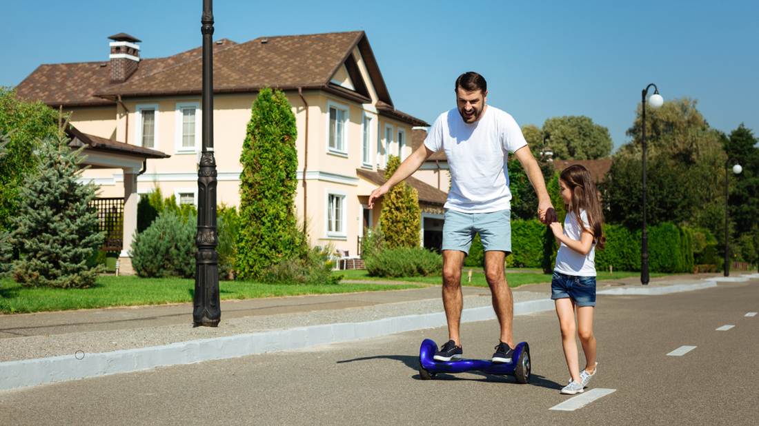 A man and child happily riding a rideo hoverboard together on a sunny day.